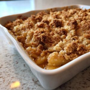 Close-up of a golden brown, bubbling 3-ingredient apple pie dump cake in a white baking dish.