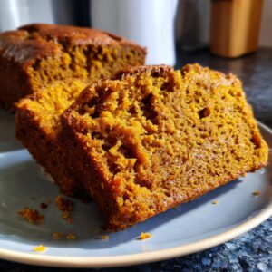 Close-up of two moist slices of the best pumpkin bread on a blue plate.