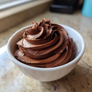 A bowl filled with smooth, swirled chocolate frosting, showcasing the rich chocolate frosting recipe.