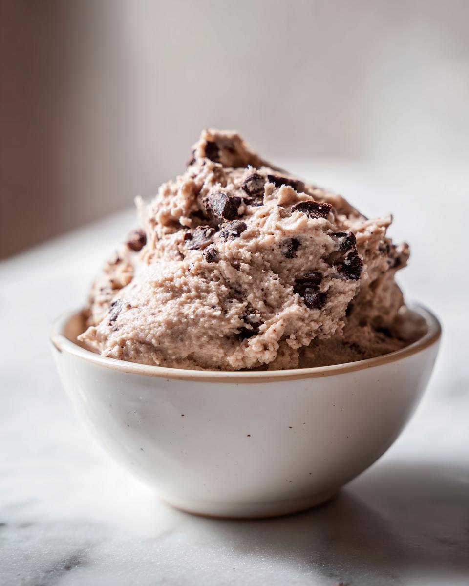 A close-up of a bowl filled with delicious high protein cookie dough, studded with chocolate chips.