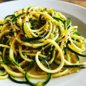 A close-up shot of a plate filled with lemon garlic zucchini noodles, sprinkled with red pepper flakes.