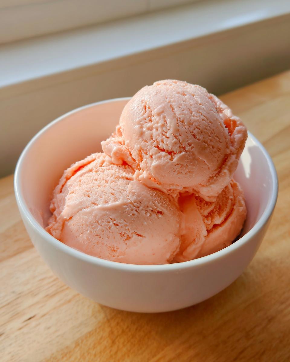 Three scoops of creamy papaya protein ice cream in a white bowl.