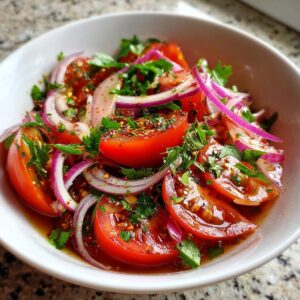 A close-up of a vibrant Portuguese tomato salad, featuring sliced ripe tomatoes, thinly sliced red onion, and fresh parsley, all tossed in a glistening dressing.