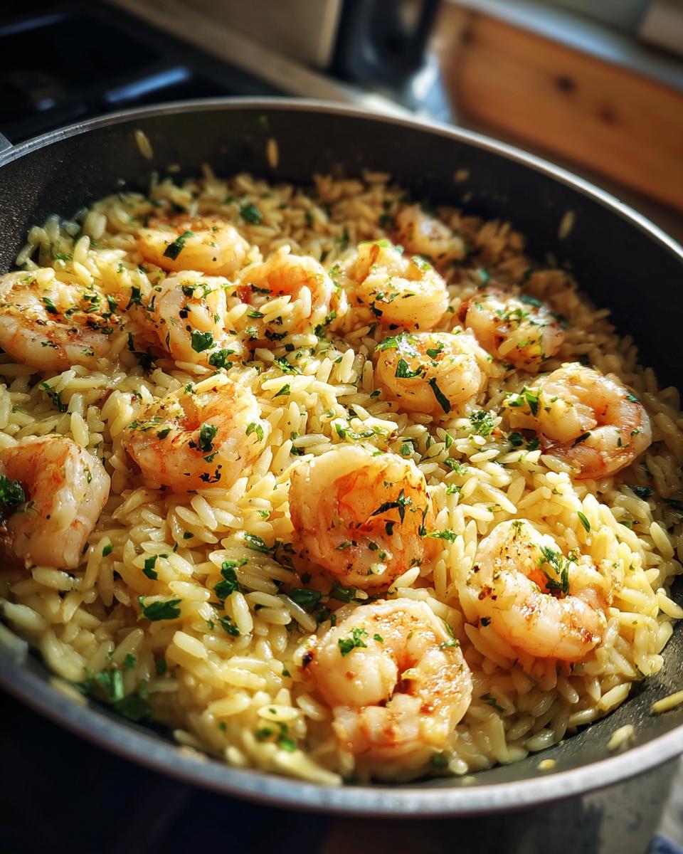 Close-up of shrimp orzo in lemon garlic sauce, garnished with parsley, in a pan.