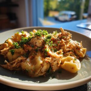 A close-up of a plate filled with crockpot chicken tortellini, topped with fresh parsley.