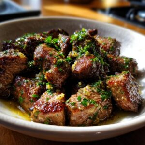 Close-up of juicy garlic butter steak tips seasoned with fresh parsley.