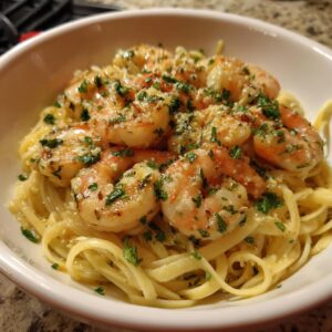 A close-up of succulent shrimp scampi served over linguine pasta, garnished with fresh parsley.