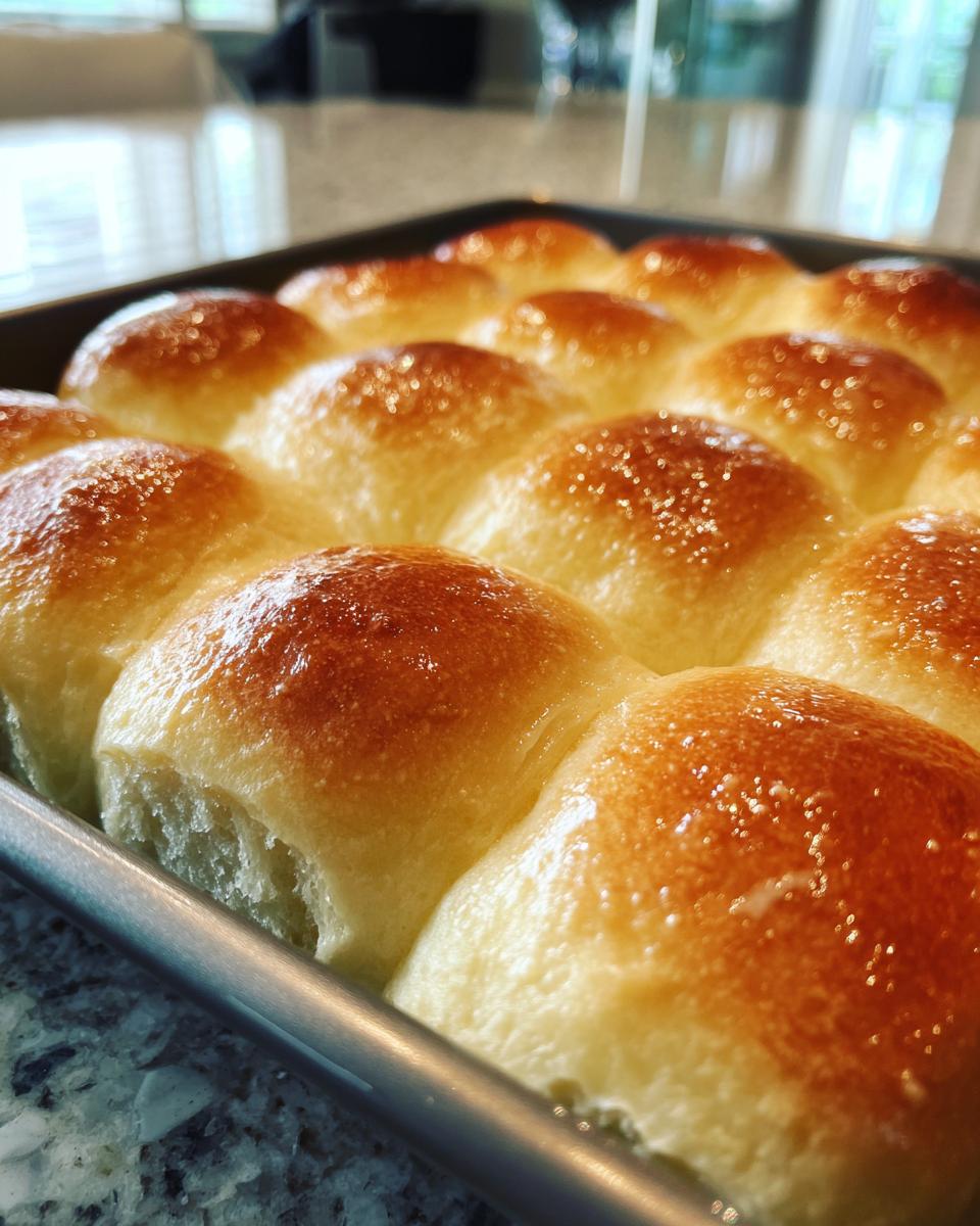 Close-up of freshly baked small batch dinner rolls with a golden brown, buttery crust in a baking pan.