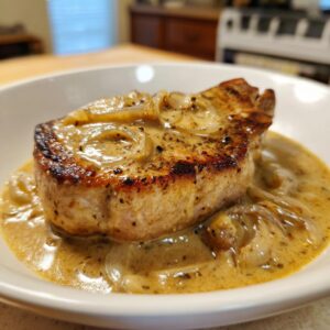 A close-up of a juicy smothered boneless pork chop in a creamy onion sauce.