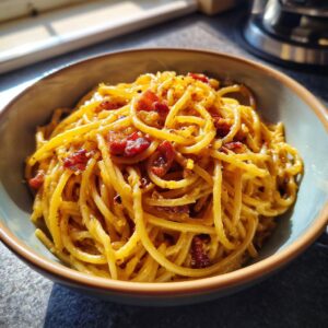 A close-up of a bowl of authentic Spaghetti Carbonara, featuring perfectly coated pasta and crispy guanciale.