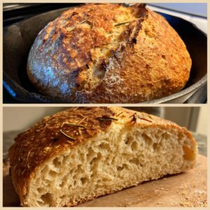 A golden brown whole wheat rosemary bread loaf, with a slice cut to show its airy crumb and fresh rosemary sprigs on top.