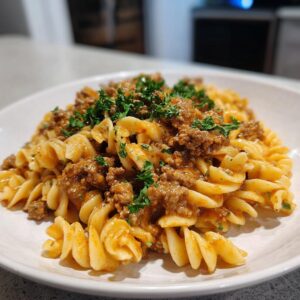 A close-up of a bowl of high protein creamy beef pasta, garnished with fresh parsley.
