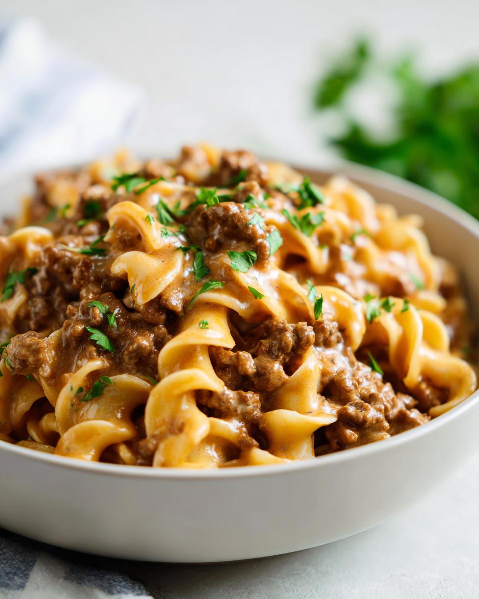 A close-up of a bowl filled with high protein creamy beef pasta, garnished with fresh parsley.