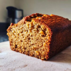 Close-up of a freshly baked moist banana bread loaf, showing its golden-brown crust and tender crumb.