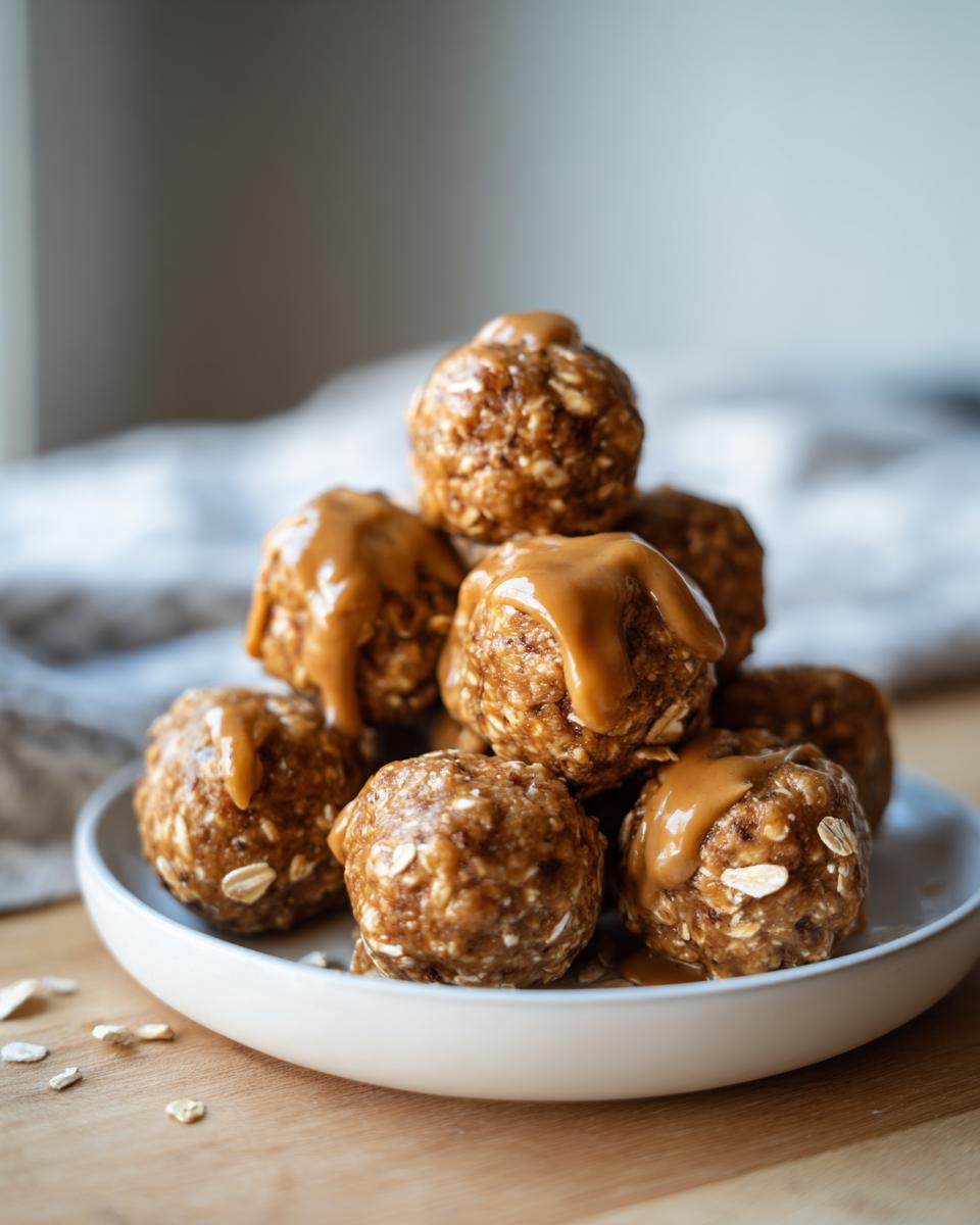 A stack of no bake protein balls drizzled with caramel sauce on a white plate, with oats scattered around.