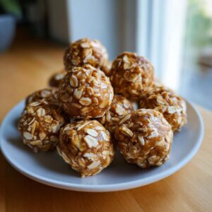 A pile of no bake protein balls made with oats and peanut butter on a white plate.