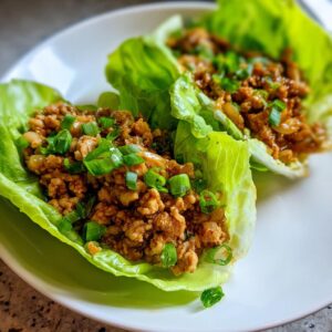 Close-up of two delicious chicken lettuce wraps filled with savory ground chicken and topped with fresh green onions.