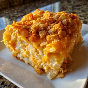 A close-up slice of creamy potato casserole topped with melted cheese and crunchy cornflakes.