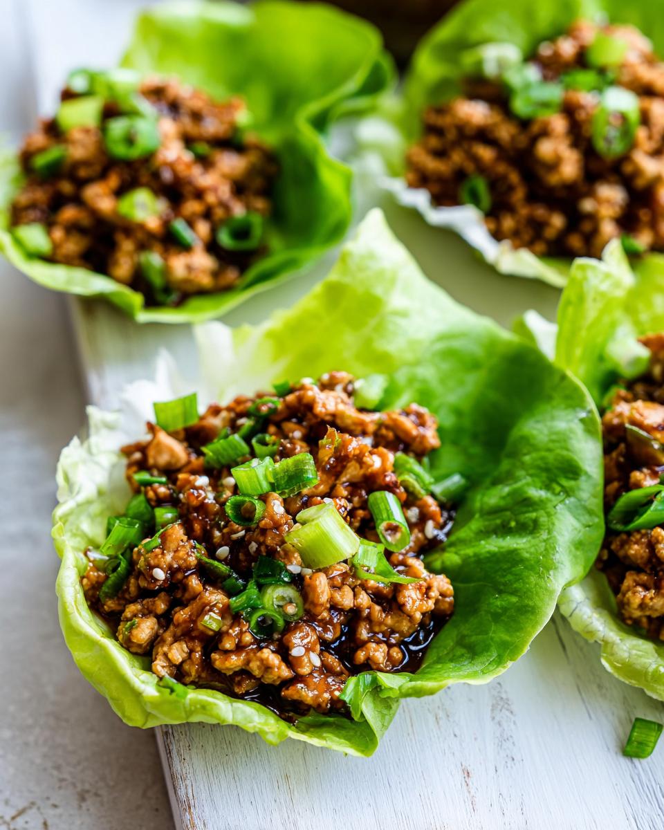Close-up of savory chicken lettuce wraps filled with ground chicken mixture and topped with green onions.