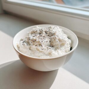A white bowl filled with creamy white coconut chia pudding, topped with extra chia seeds.