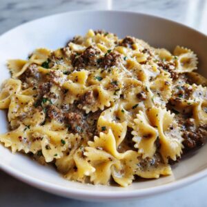 Close-up of creamy parmesan garlic beef bowtie pasta coated in a rich sauce and garnished with parsley.