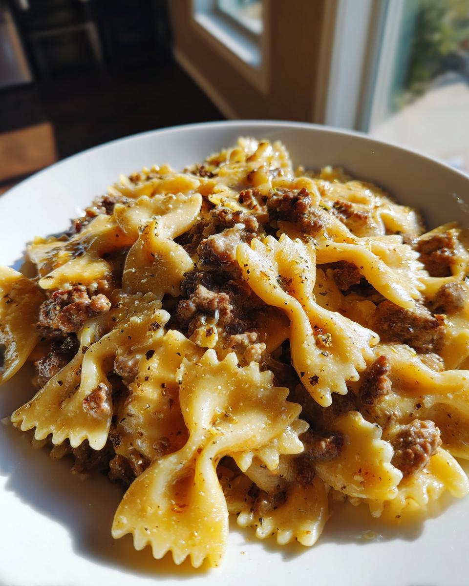 A close-up bowl of creamy parmesan garlic beef bowtie pasta, glistening under natural light.