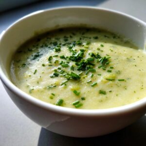 Close-up of a bowl of creamy potato leek soup garnished generously with chopped fresh chives.