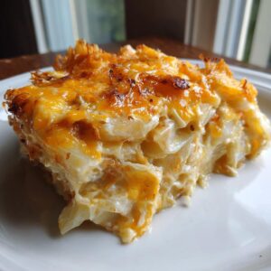 A generous serving of crockpot cheesy potatoes showing layers of creamy potatoes and a golden brown, bubbly cheese topping.