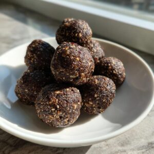 A pile of dark, textured protein balls coated in seeds sitting on a small white plate.