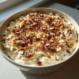 A creamy, baked Neiman Marcus Dip topped generously with crumbled bacon and sliced almonds.