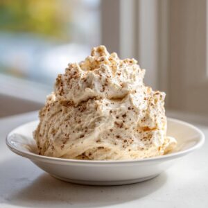 A large, fluffy mound of homemade cinnamon butter sprinkled with ground cinnamon in a white bowl.