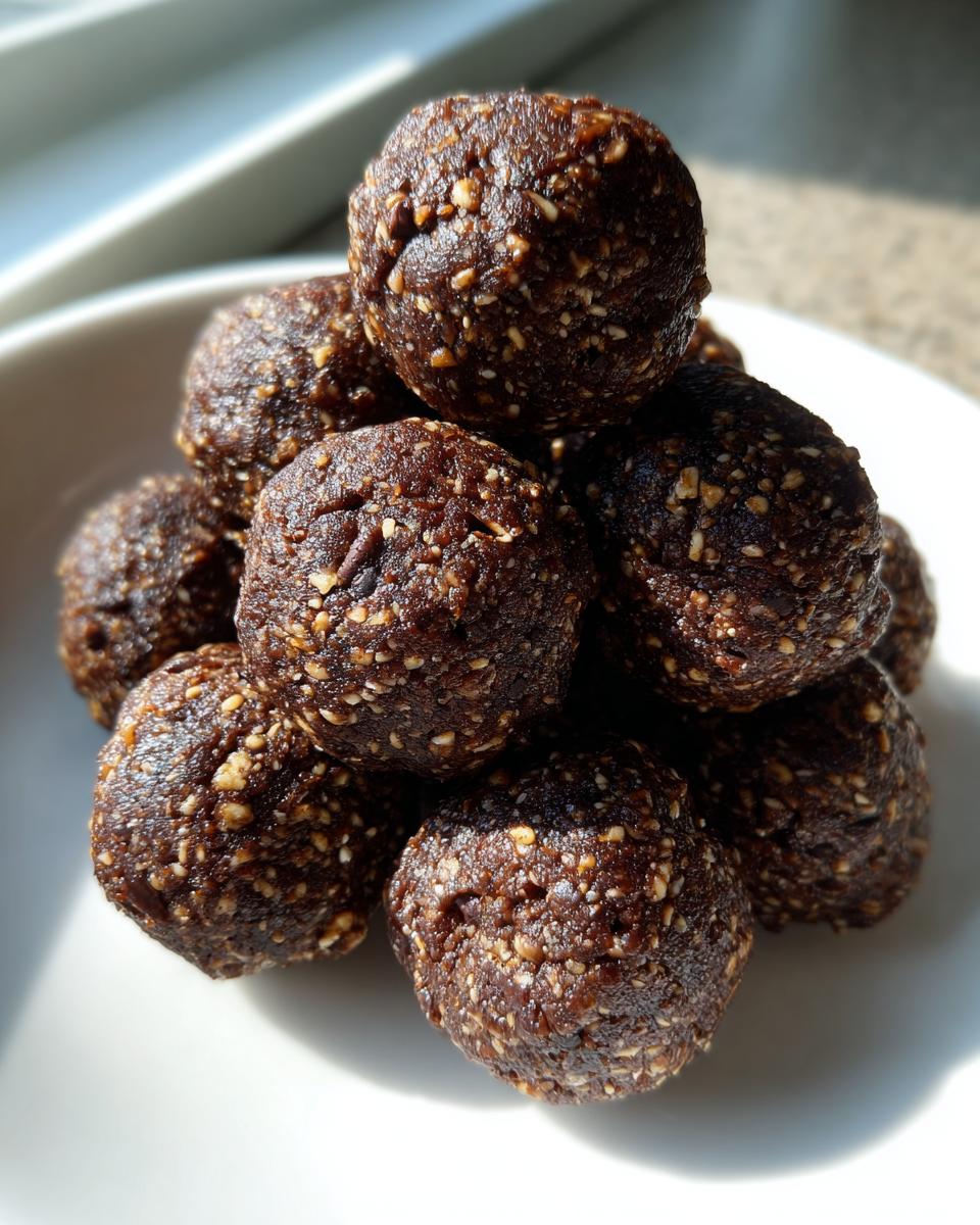 A close-up stack of dark, textured protein balls coated in visible seeds, sitting on a white plate.