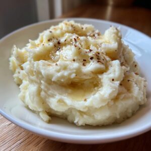 Close-up of fluffy garlic mashed potatoes drizzled with melted butter and toasted garlic bits.