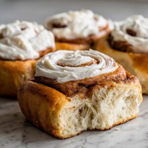Close-up of a fluffy sourdough discard cinnamon roll with cream cheese frosting, showing the soft interior texture.