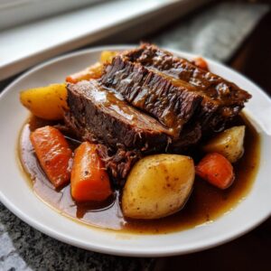 Close-up of tender, sliced pot roast served with carrots and potatoes in rich gravy.