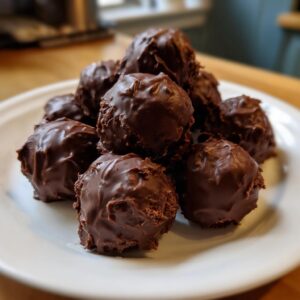 A close-up of a mound of rich, chocolate-coated Oreo balls stacked on a white plate.