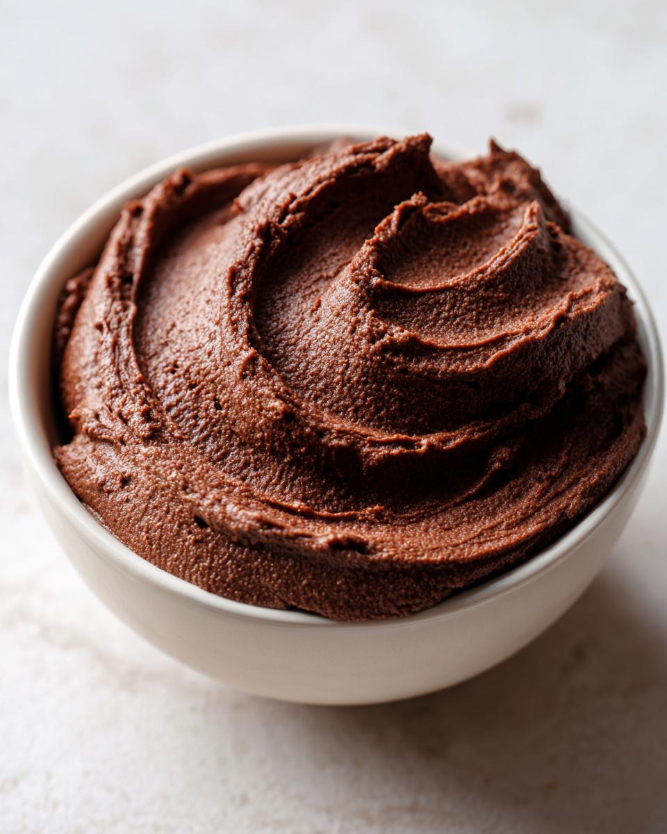 Close-up of a creamy, dark brown chocolate dip swirled beautifully in a small white bowl.