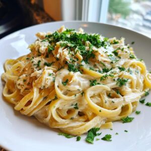 A close-up of creamy crab pasta featuring fettuccine noodles coated in a rich white sauce, topped with shredded crab meat and fresh parsley.
