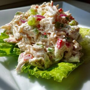 A mound of creamy crab salad mixed with celery and red onion served on a crisp green lettuce leaf.