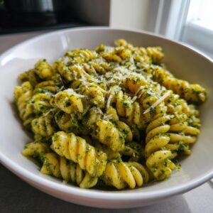 Close-up of creamy pesto pasta made with fusilli noodles, topped with grated Parmesan cheese.