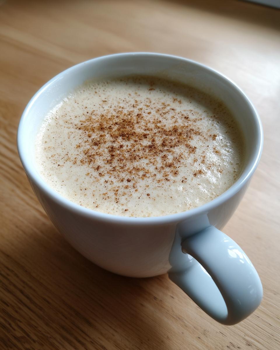 Close-up of a white mug filled with creamy roasted cauliflower soup, topped with a sprinkle of spices.