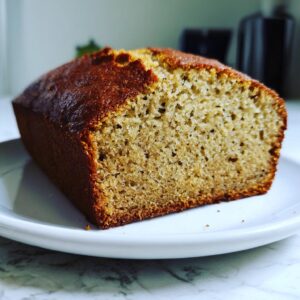 Close-up of a slice of golden brown greek yogurt banana bread showing its moist, tender crumb texture.