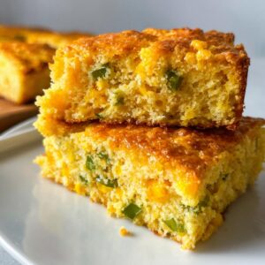 Two stacked, moist slices of Mexican cornbread showing corn kernels and green jalapeño pieces inside.