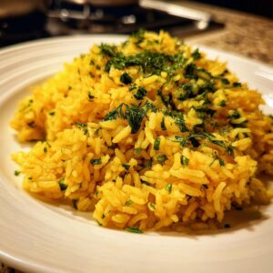 Close-up of fluffy, yellow mediterranean rice seasoned and topped generously with chopped fresh dill and parsley.