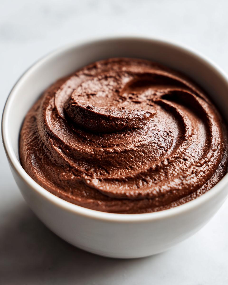 Close-up of rich, dark brown chocolate dip swirled beautifully in a small white bowl.