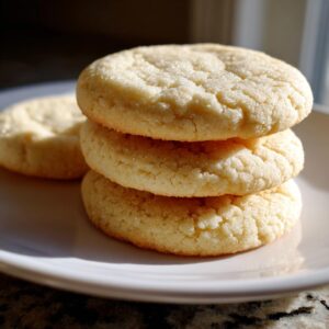 Close-up of three stacked, round, soft sugar cookies coated in sparkling sugar.