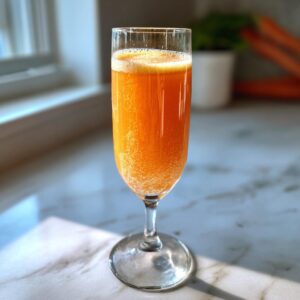A vibrant, bubbly orange bellini recipe served in a tall champagne flute on a marble countertop.