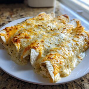 Close-up of three baked white chicken enchiladas covered in melted white and orange cheese sauce.